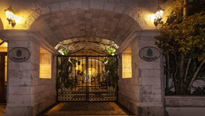 An arched entrance with a wrought iron gate, stone walls, and two illuminated wall sconces. - Fabiola Condo Hotel (Playa del Carmen)