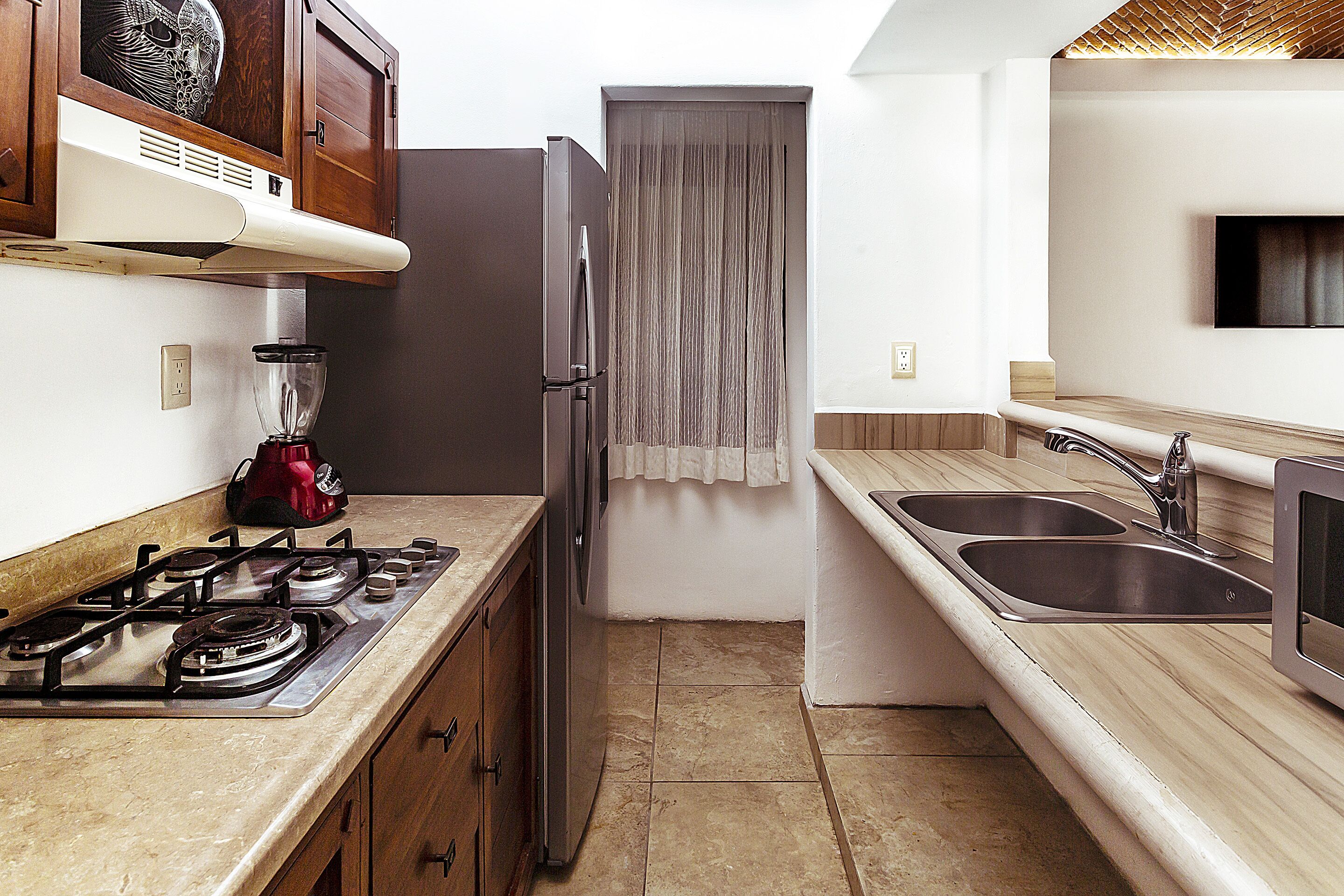 Una cocina compacta con estufa a gas, refrigerador, pileta y microondas.