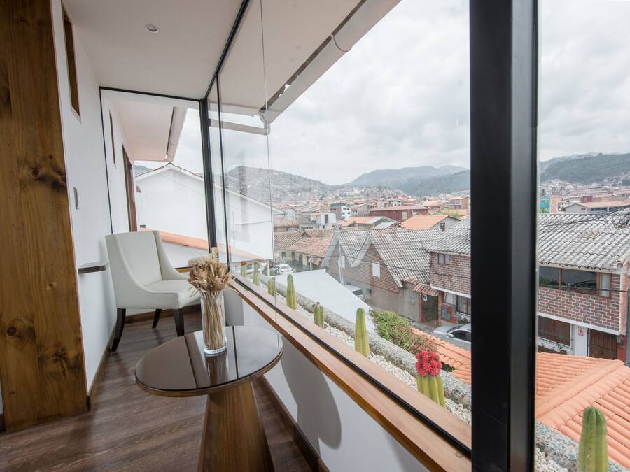 A modern room with a balcony, white walls, a wooden floor, a round table, and a chair.