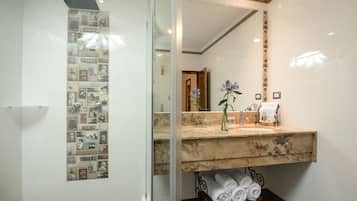A bathroom with a large mirror, a marble sink, and a towel rack with folded towels.