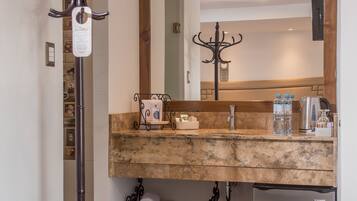 A modern bathroom with a marble countertop, a built-in sink, a mirror, and a stainless steel refrigerator.