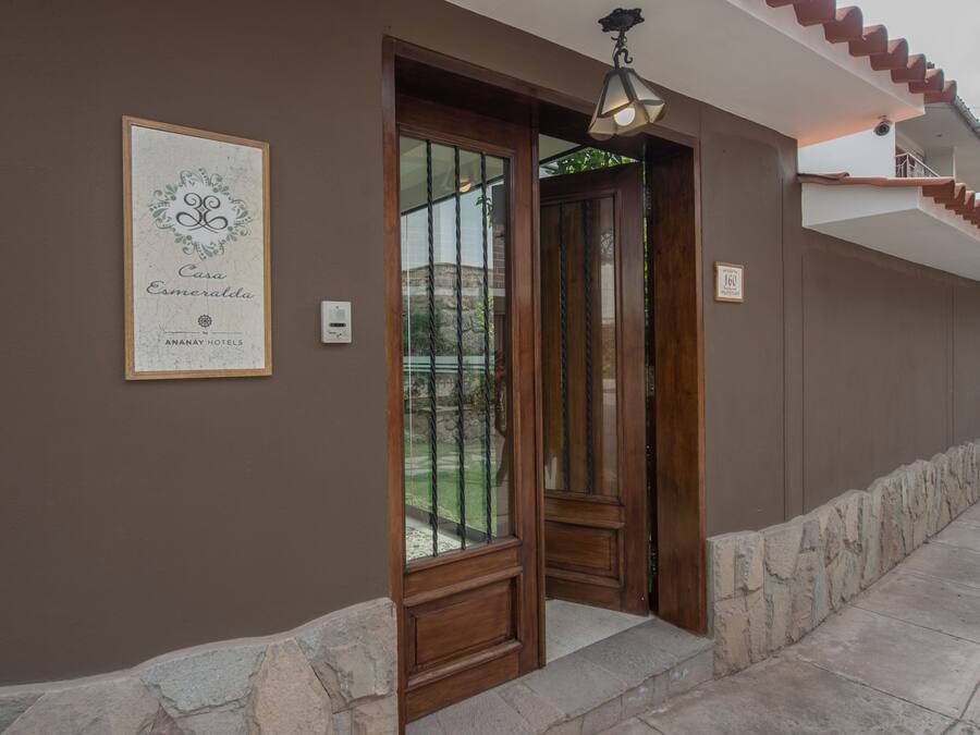 A hotel entrance with a wooden door, a framed sign above the door, and a stone wall beside the entrance.