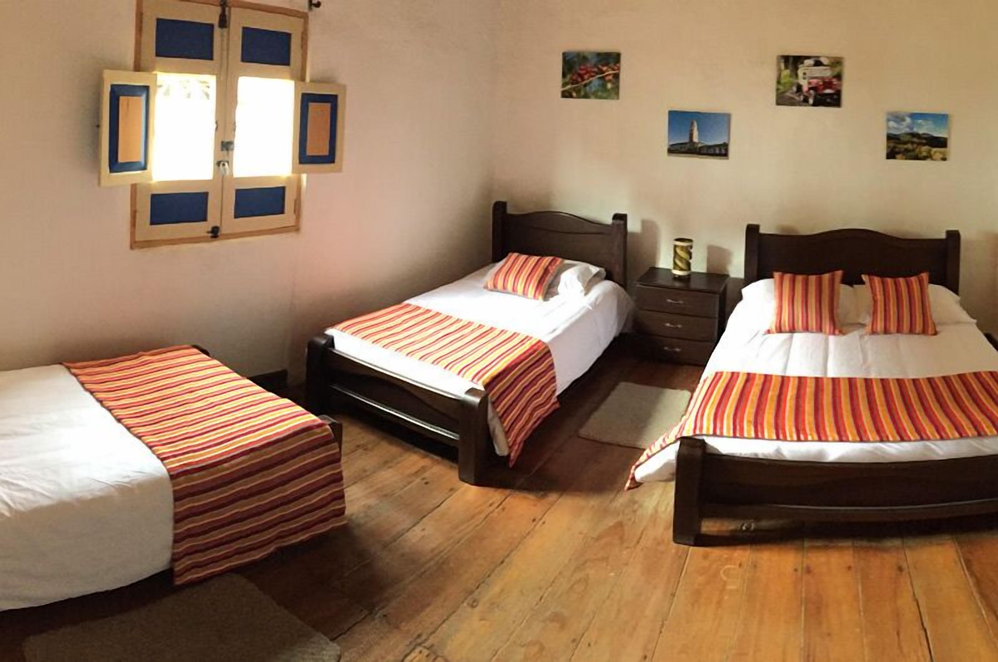 Ein Zimmer mit zwei Einzelbetten, Holzboden und einem Fenster mit Jalousien.
