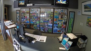 A reception desk with a computer, papers, and a bulletin board filled with travel brochures. - Global Backpackers - Port Douglas (Port Douglas)