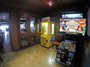 A claw machine arcade game, a general store with a sign advertising Big Buck, and a television screen displaying a game. - Global Backpackers - Port Douglas (Port Douglas)