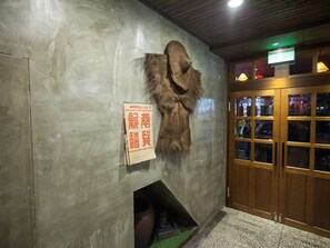 A room with a fur coat mounted on the wall, a wooden door with glass panels, and a sign with red text. - Jian Shan Hotel (Taipei)