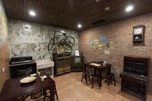 A room with a brick wall, a bicycle hanging, a vintage radio, a television, and a dining table with chairs. - Jian Shan Hotel (Taipei)