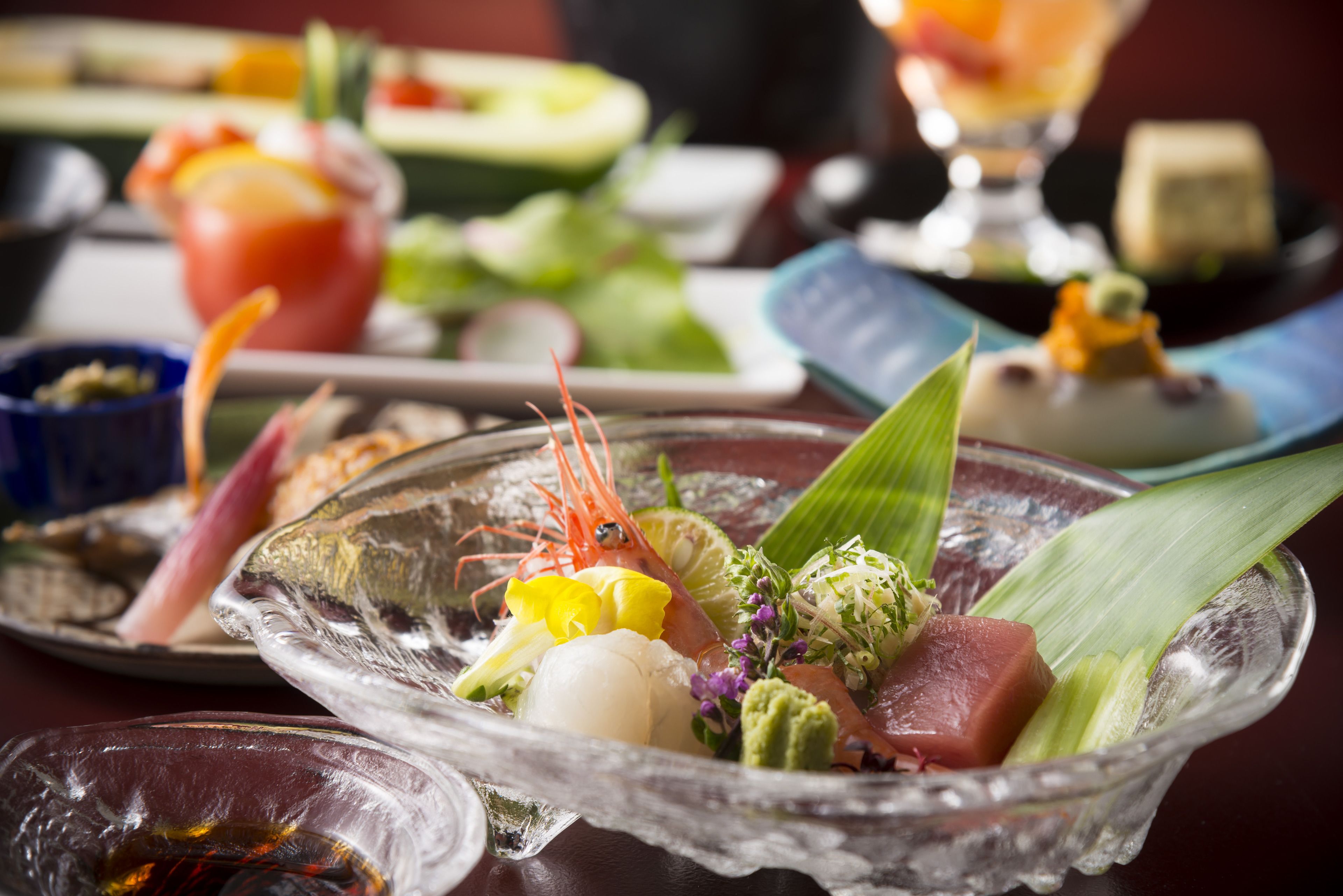 Une variété de plats sont disposés sur la table, notamment des sashimis et d’autres fruits de mer.