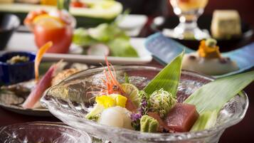 Une variété de plats sont disposés sur la table, notamment des sashimis et d’autres fruits de mer.