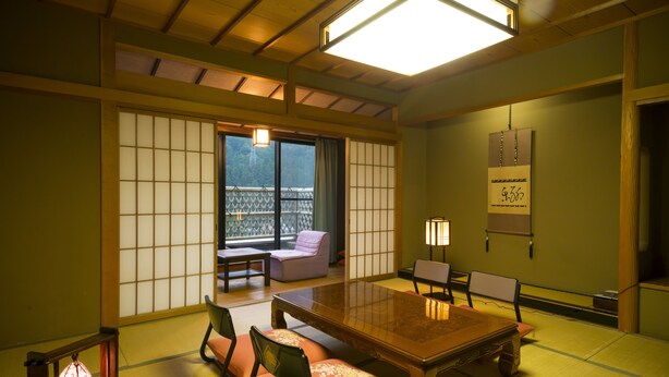 A traditional Japanese room with tatami flooring, a low table, and cushions. - Suzuya Konnichiro (Kaga)