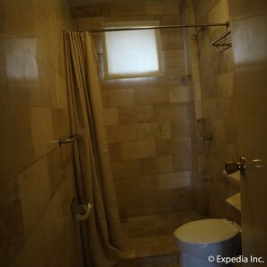 Un baño con ducha, inodoro y ventana.
