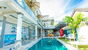 Zona de piscina con barandilla de vidrio, sillas de descanso y enfriador de Coca-Cola.