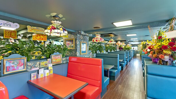 A restaurant with booths and tables, featuring vibrant colors and floral decorations. - Hotel New Ohte (Hakodate)