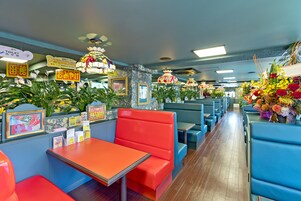 Un restaurante con cabinas y mesas, con colores vivos y decoración floral.