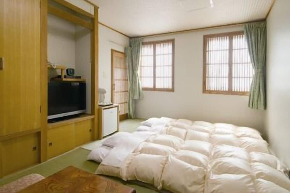 A room with a bed, a television, a desk, and a wardrobe.