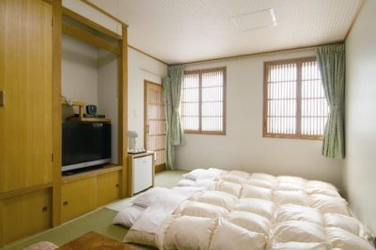 A room with a bed, a television, a desk, and a wardrobe.