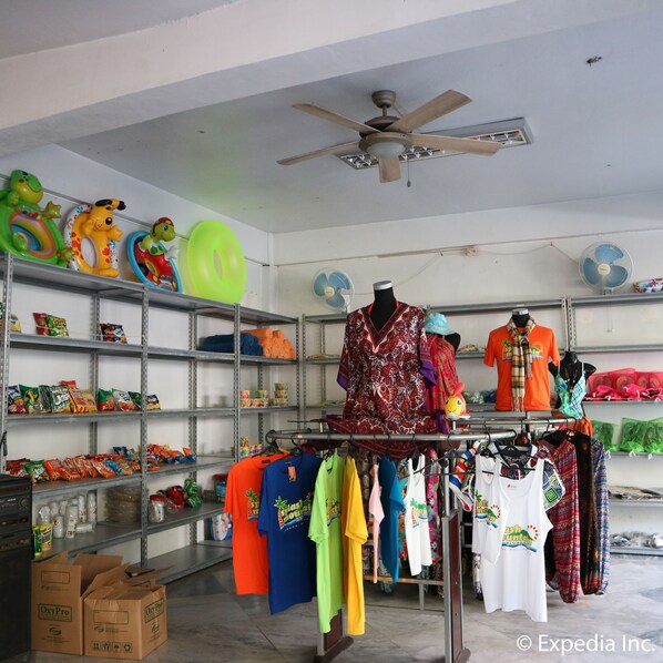 A retail store with shelves stocked with snacks and clothing racks displaying various t-shirts. - Splash Mountain Resort Hotel (Los Banos)