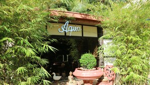 A garden entrance with a sign reading "Aqua," surrounded by bamboo plants and decorative pots. - Splash Oasis Resort Hotel (Los Banos)