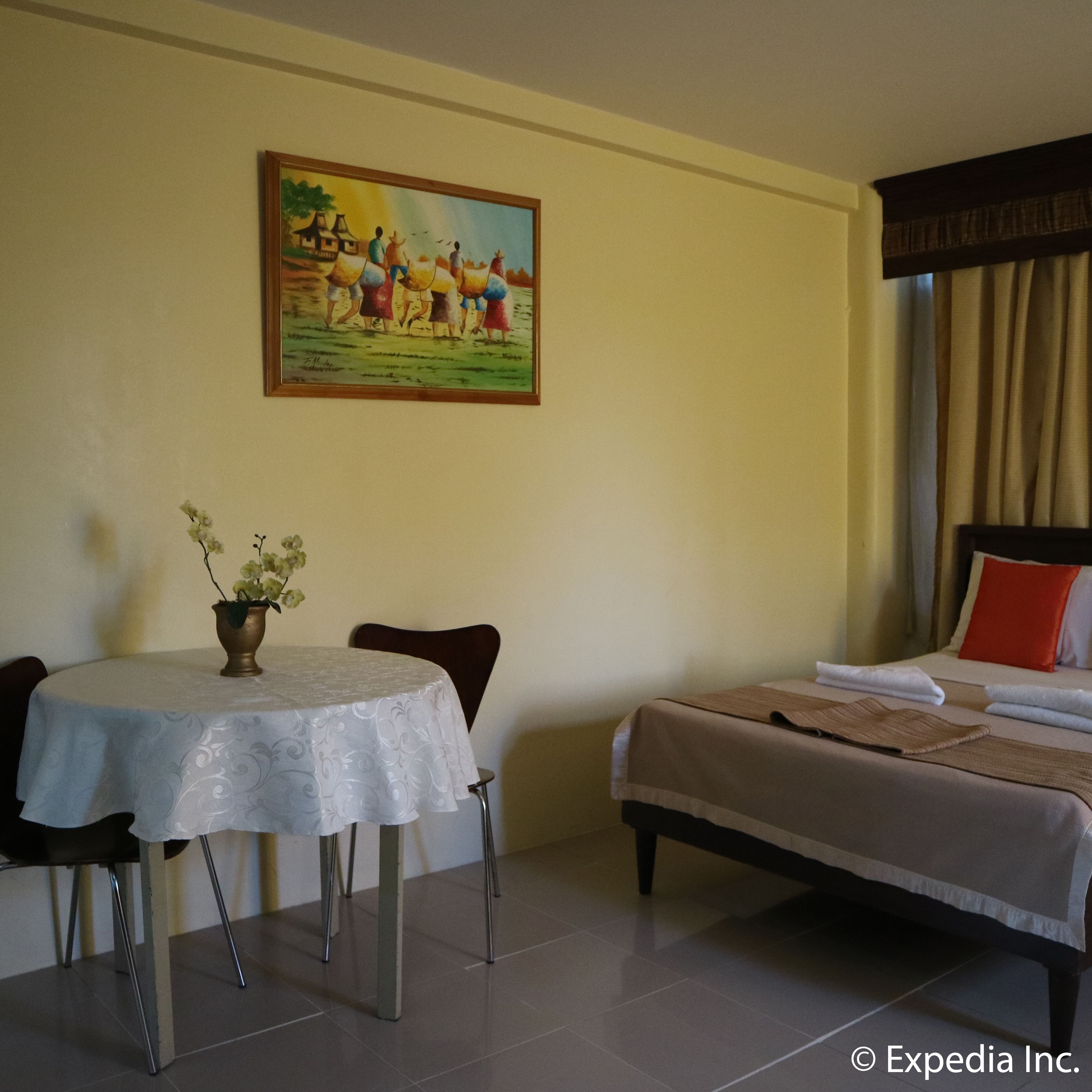 Una habitación de hotel con cama, una mesa de comedor con sillas y un cuadro en la pared.