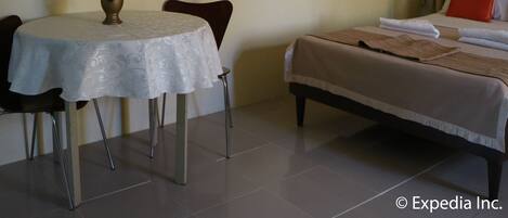 Una habitación de hotel con cama, una mesa de comedor con sillas y un cuadro en la pared.