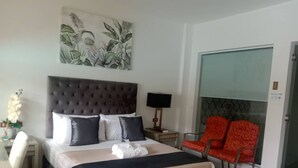 A hotel room with a bed, a chair, a desk, and a painting on the wall. - Splash Oasis Resort Hotel (Los Banos)