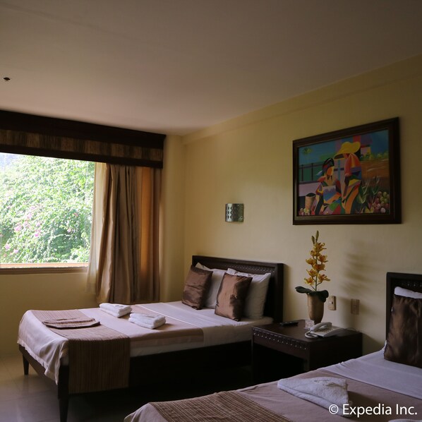 Une chambre d’hôtel avec deux lits, un tableau au mur, une fenêtre avec des rideaux et un vase de fleurs sur la table de chevet.