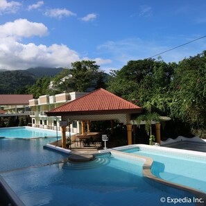 Un hôtel doté de plusieurs piscines, d’un espace de détente couvert et d’une végétation luxuriante.