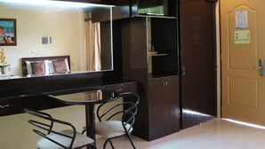A hotel room with a bed, a desk with chairs, a mirror, a wardrobe, and a door. - Splash Oasis Resort Hotel (Los Banos)