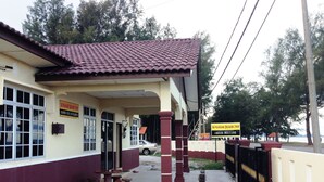 A building with a tiled roof, a covered entrance, and a signboard.