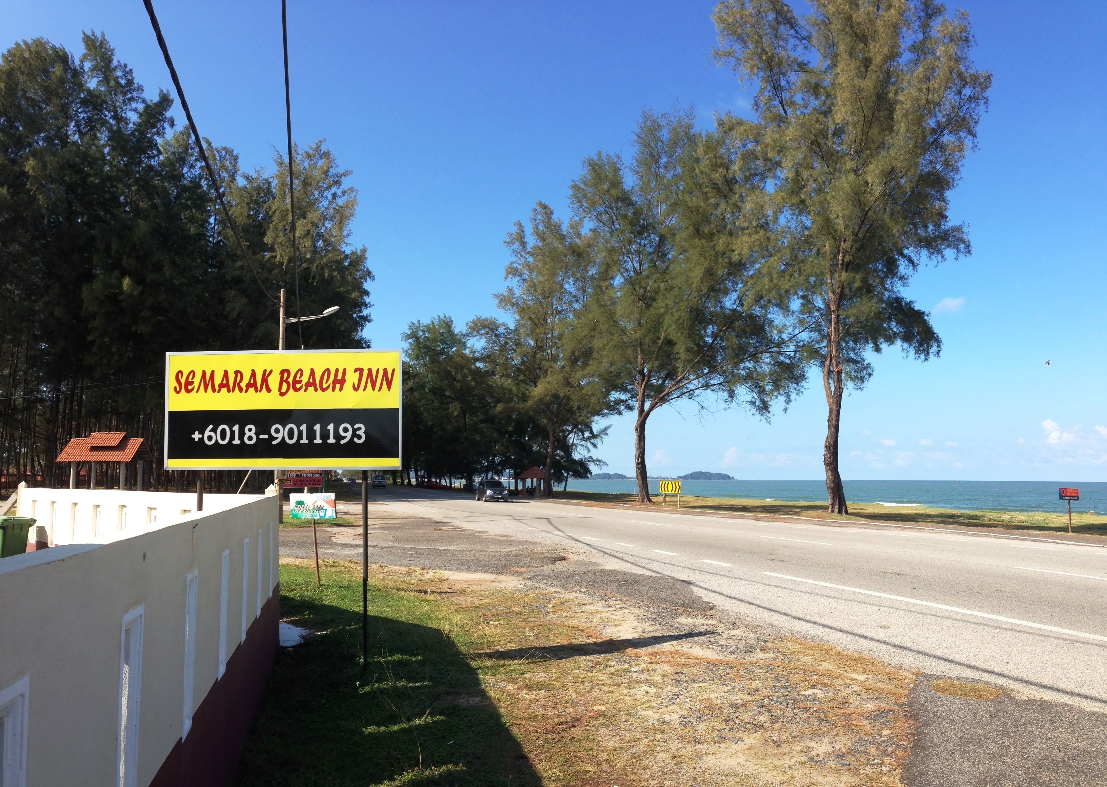 A beach view with a sign for 'Semarak Beach Inn' and a contact number.