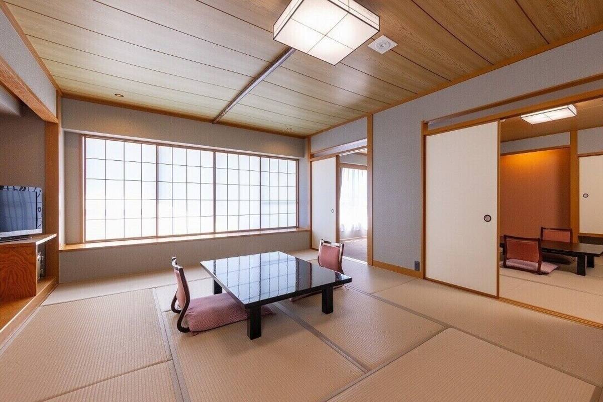 A traditional Japanese room with tatami flooring, a low table, and sliding doors.