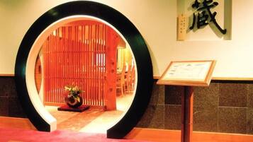 Uma área de recepção com moldura circular de madeira, uma placa com caracteres chineses e um certificado emoldurado sobre um suporte.