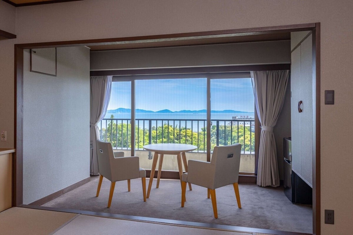 Una habitación con balcón, una mesa redonda y dos sillas.