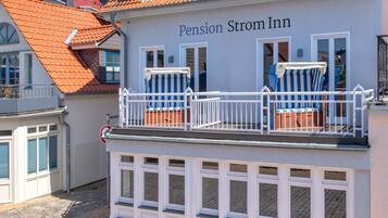 Um edifício chamado Pension Strom Inn com uma varanda que apresenta duas cadeiras de praia listradas e uma pequena mesa.