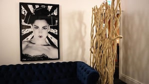 A dark blue sofa, a black and white poster, and a wooden structure. - Contact Hôtel le Provence (Agen)