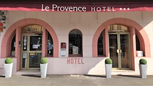 The facade of Le Provence Hotel with three arched entrances, a prominent 'HOTEL' sign, and several posted notices. - Contact Hôtel le Provence (Agen)
