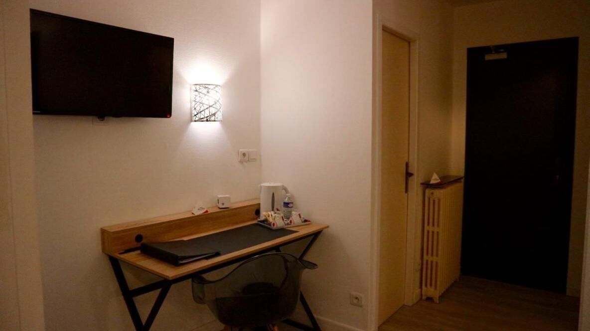 A small room with a desk, chair, and a flat-screen TV mounted on the wall.