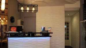 A reception desk with a modern design, a clock, and a sign for the Contact Hotel. - Contact Hôtel le Provence (Agen)