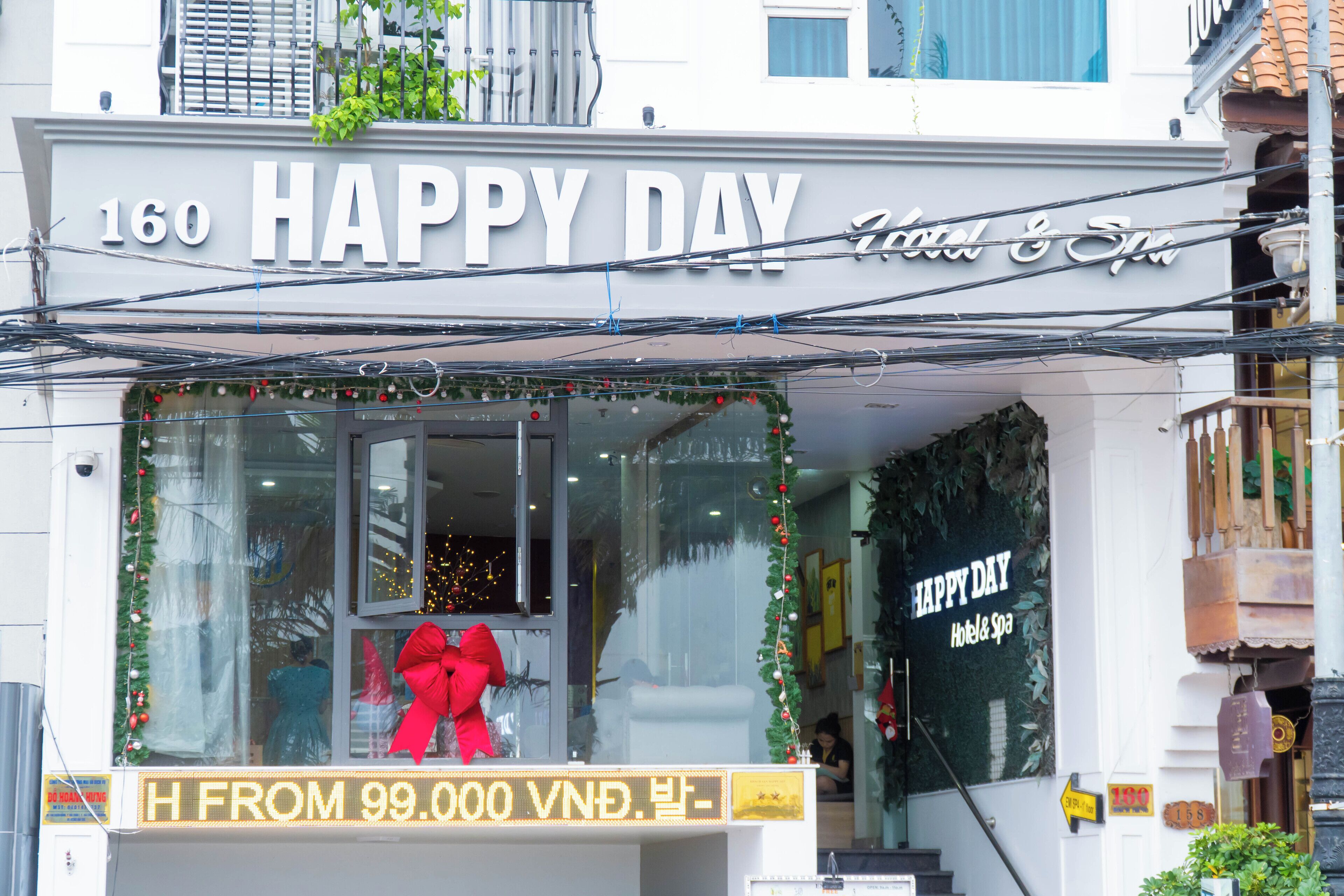 A hotel entrance with a 'Happy Day' sign, a red bow decoration, and a price display.