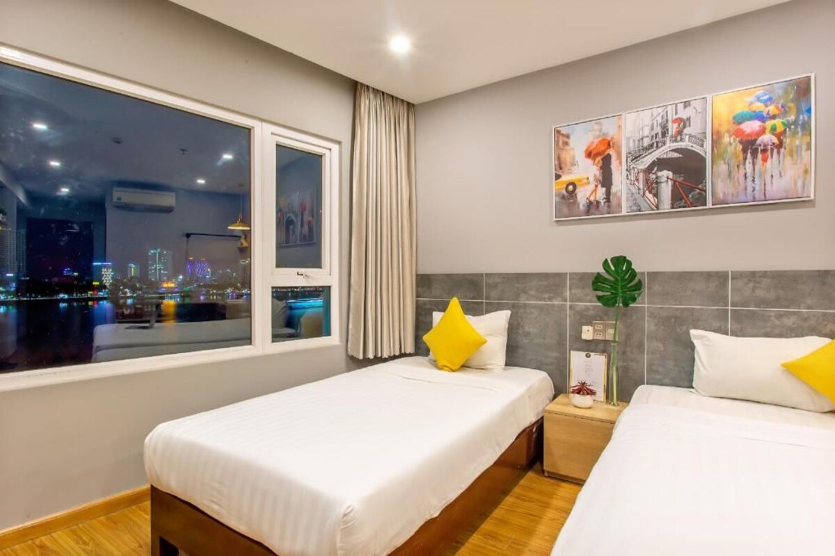 Ein Hotelzimmer mit zwei Betten, Blick auf die Stadt, einem Gemälde und einer Pflanze.