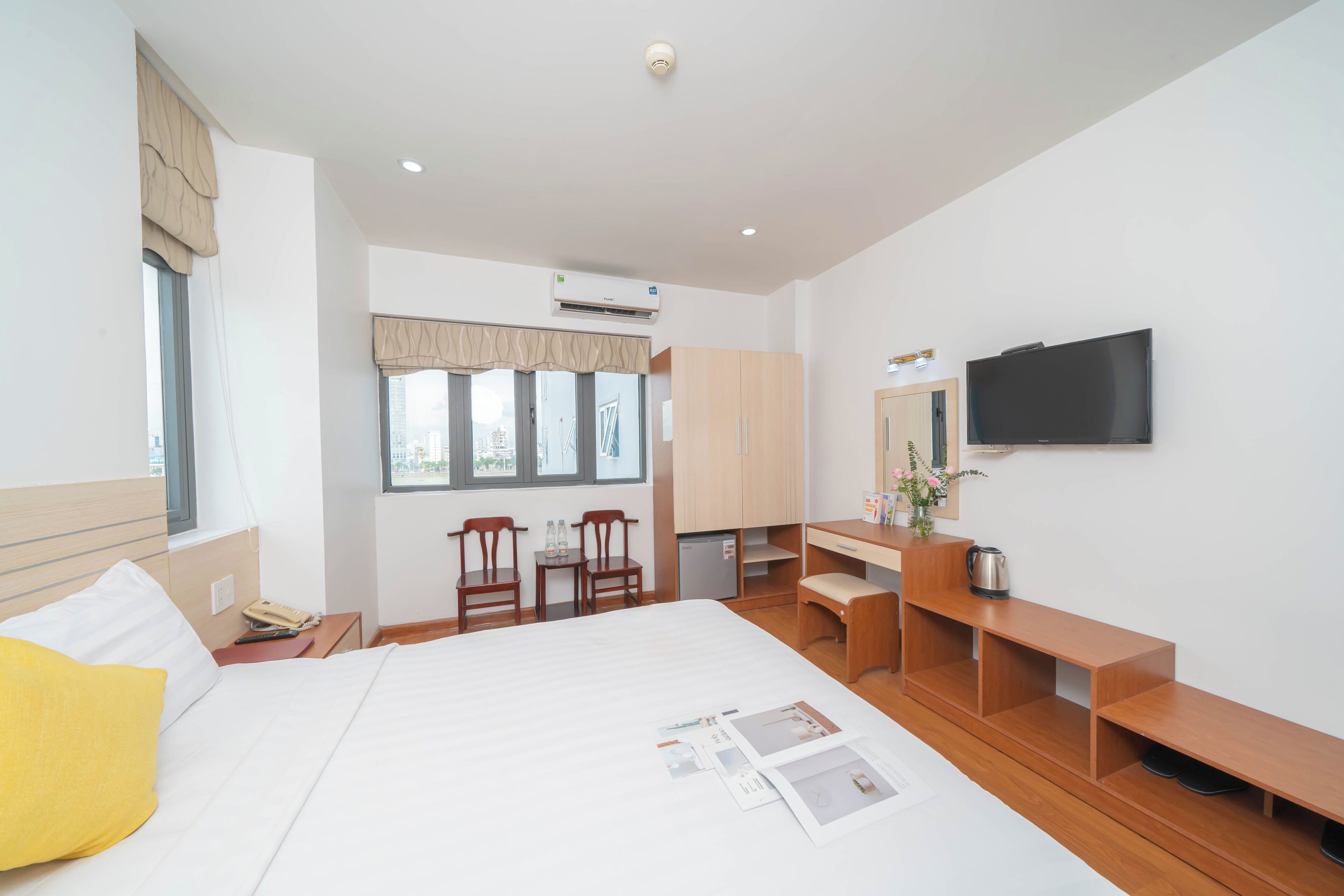 A hotel room with a bed, a desk, a chair, a television, and a window with curtains.