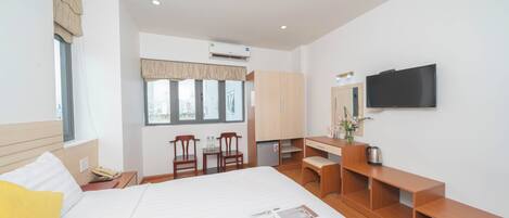 A hotel room with a bed, a desk, a chair, a television, and a window with curtains.