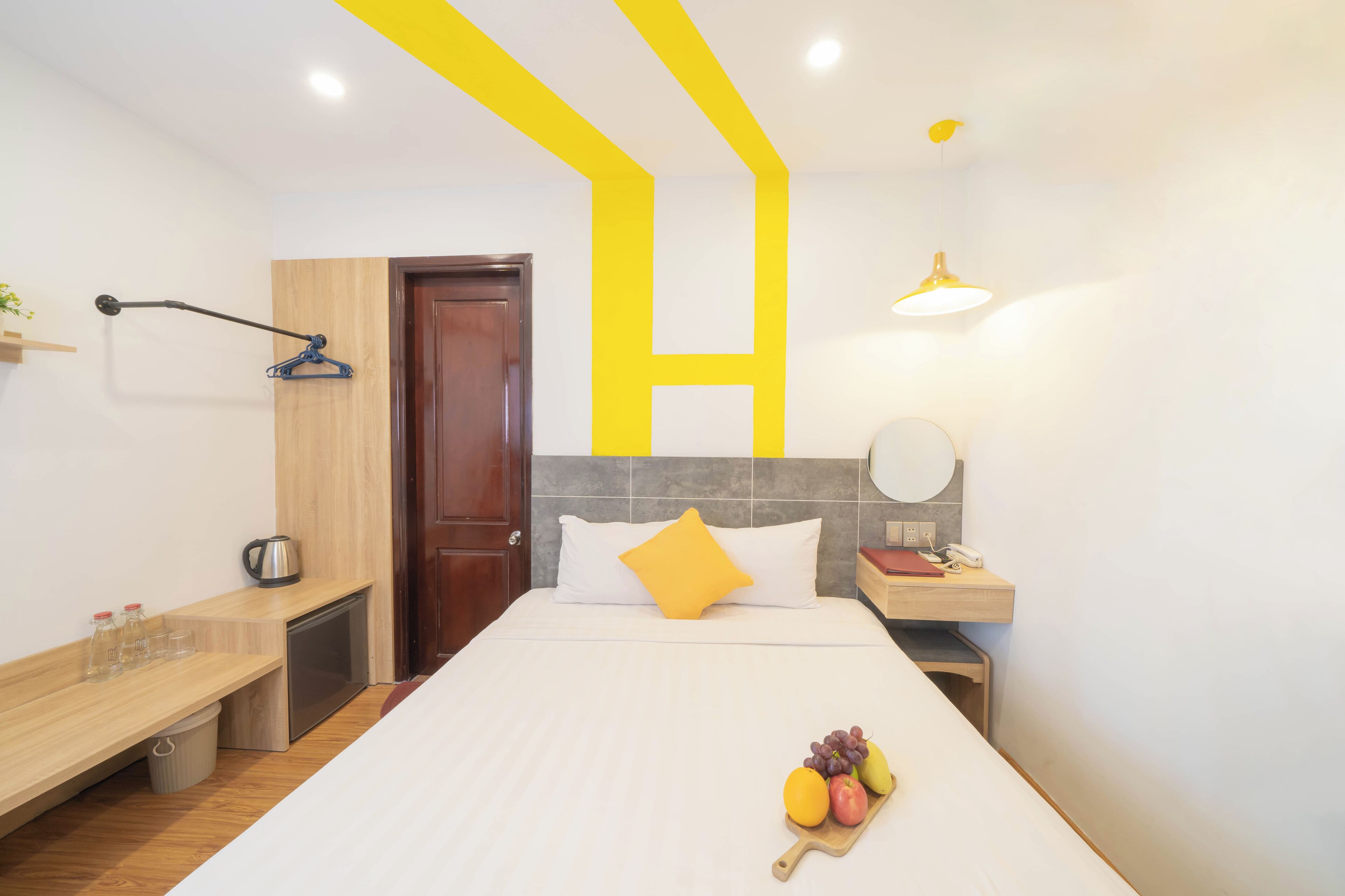 Una habitación de hotel con cama, mesita de noche y un pequeño escritorio.