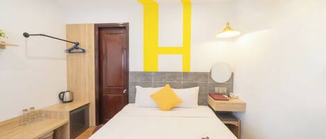 Una habitación de hotel con cama, mesita de noche y un pequeño escritorio.
