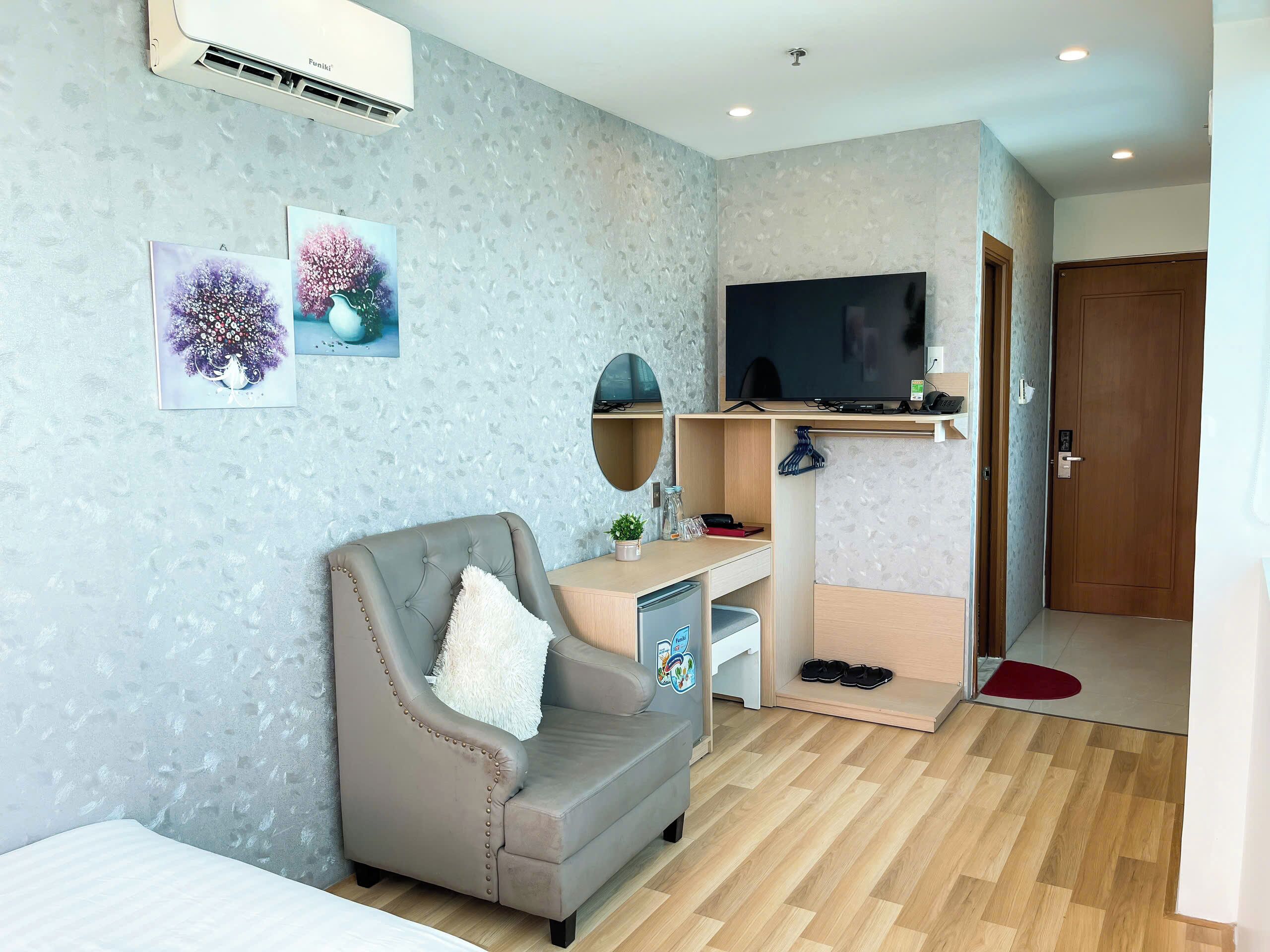 Una sala de estar moderna con un sillón gris, un televisor de pantalla plana y un escritorio de madera.