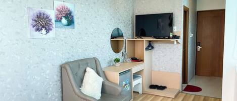 Una sala de estar moderna con un sillón gris, un televisor de pantalla plana y un escritorio de madera.