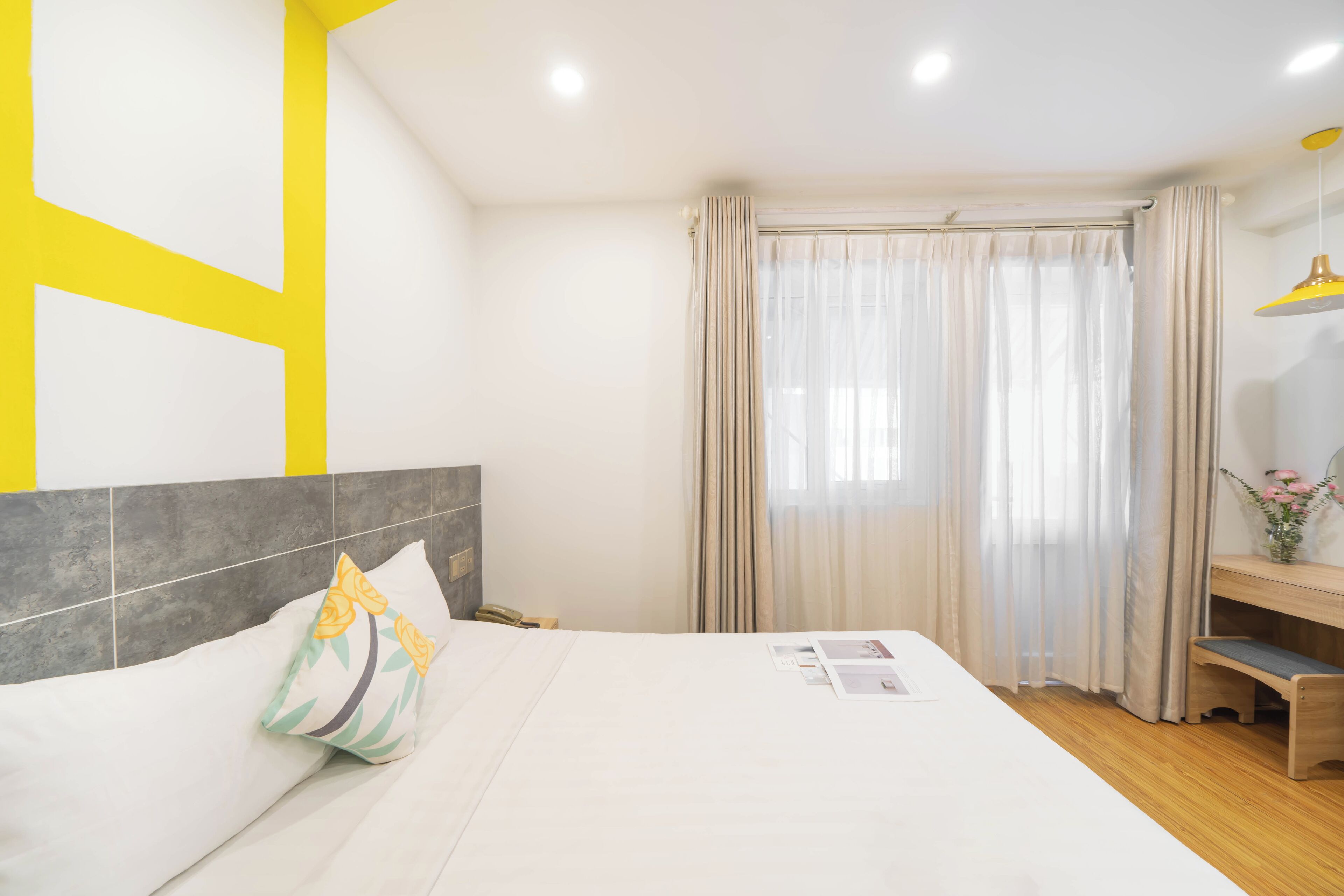 A hotel room with a bed, a desk, and a window with curtains.