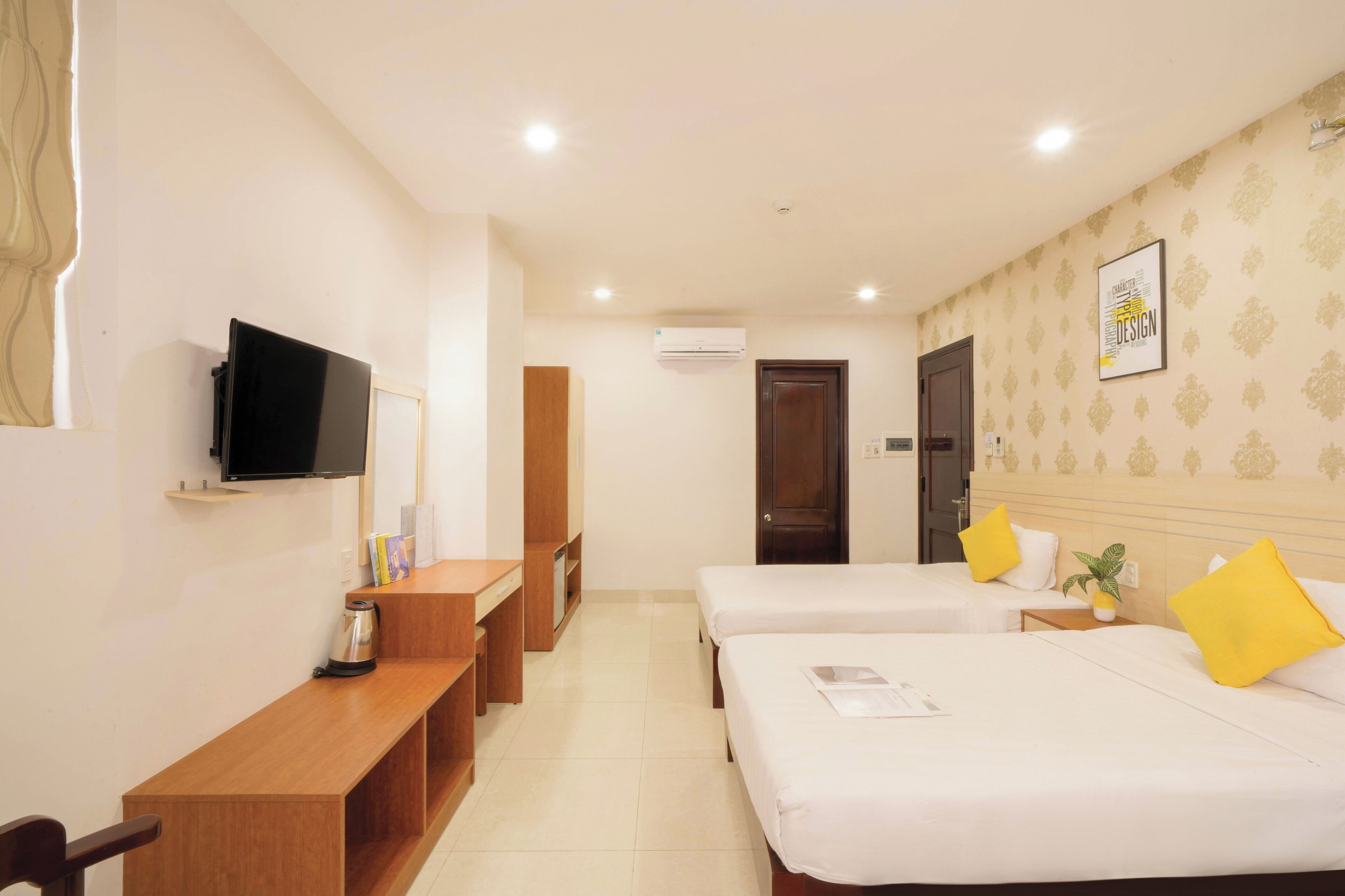 Habitación de hotel con dos camas, un escritorio, un televisor y una puerta.