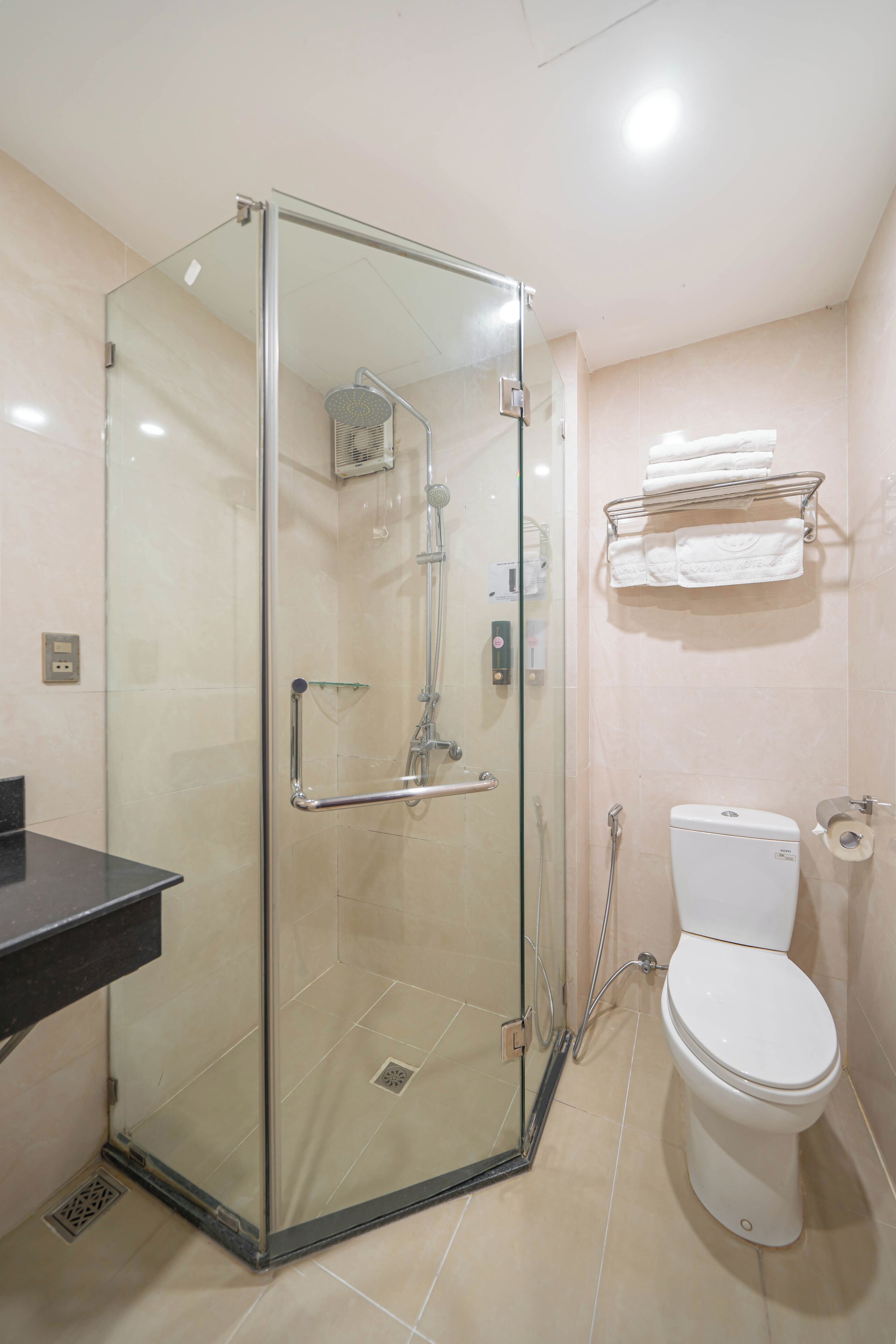 Une salle de bain moderne avec une douche à parois de verre, des toilettes blanches et un porte-serviettes.