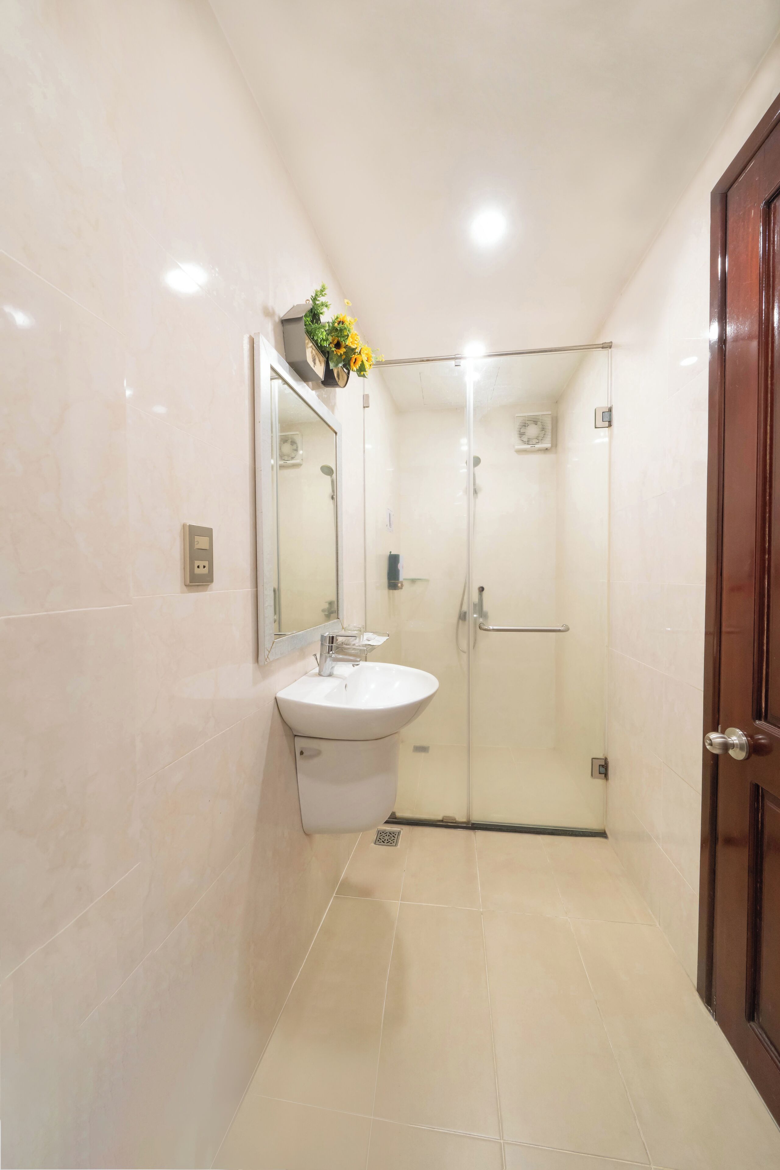 A modern bathroom with a glass-enclosed shower, a white sink, and a mirror above it.